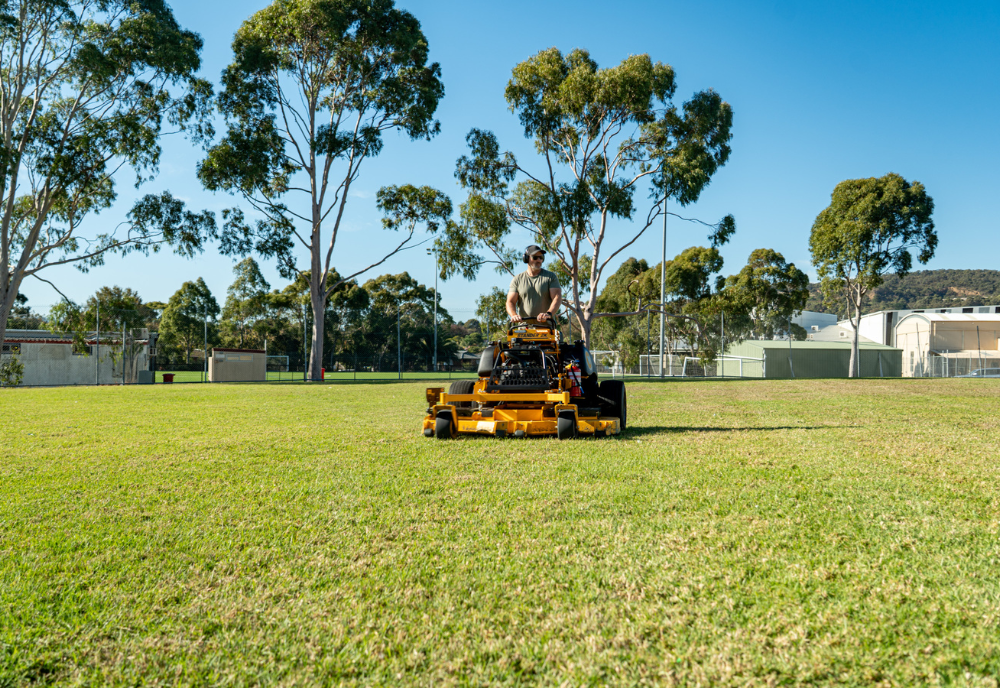 Professional operator mowing expansive grounds with a riding lawn mower in Melbourne’s eastern suburbs