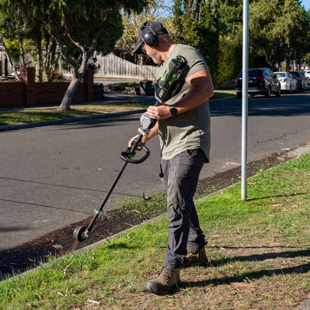 Lawn care professional mowing grass with battery-powered cutter in Melbourne’s eastern suburbs